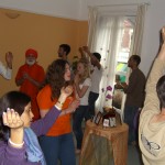 crowded room of many devotees singing around a table